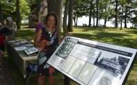 Lezlie Harper stands next to a Niagara Movement plaque at Waverly Beach Park.